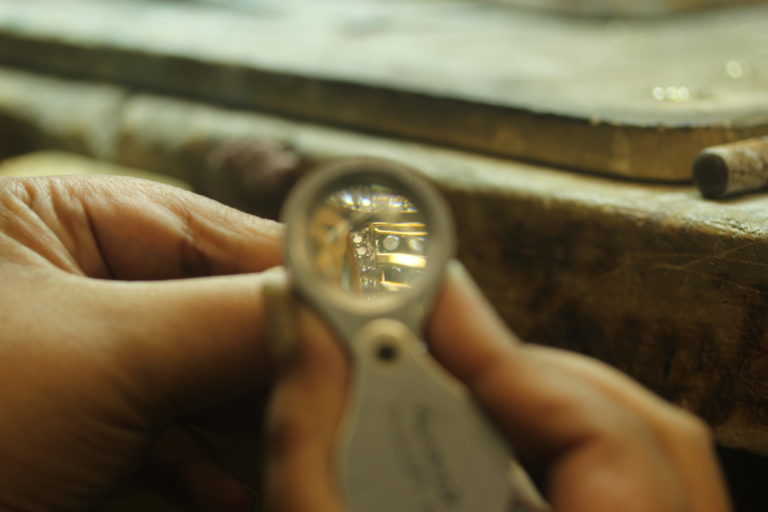 A jeweler inspects a ring through a loupe
