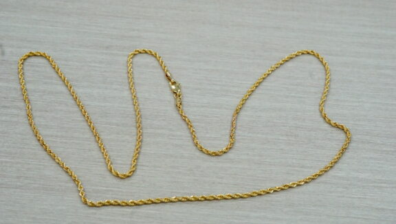 Gold rope chain laid out on a grey background